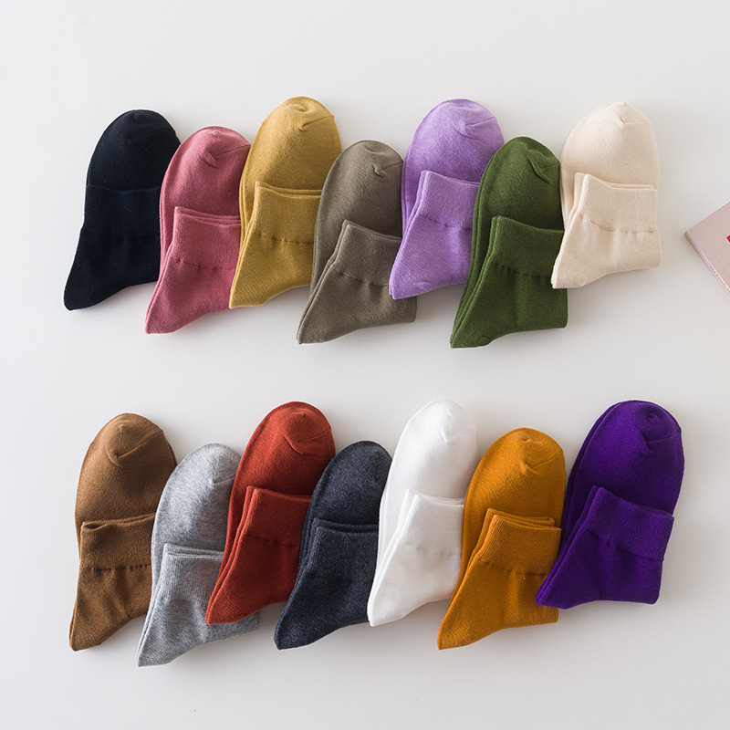 A collection of socks in various solid colors displayed both individually on a person's foot and as a collection on a flat surface.