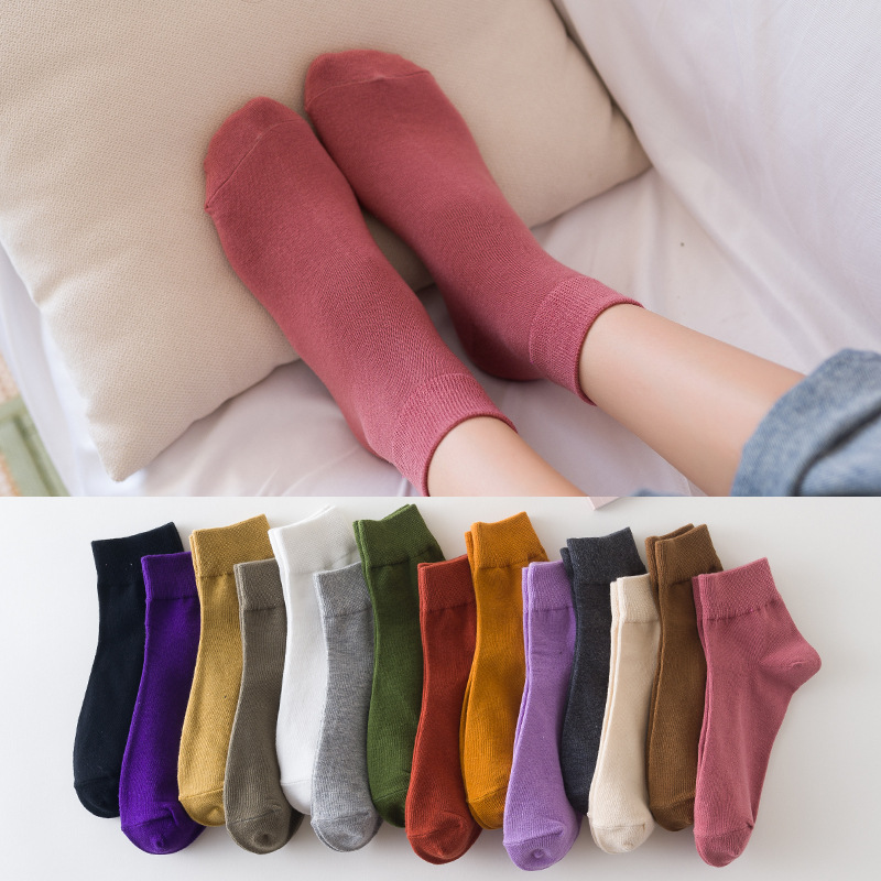 A collection of socks in various solid colors displayed both individually on a person's foot and as a collection on a flat surface.