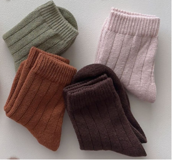Four pairs of knitted socks in green, brown, pink, and brown on a light background