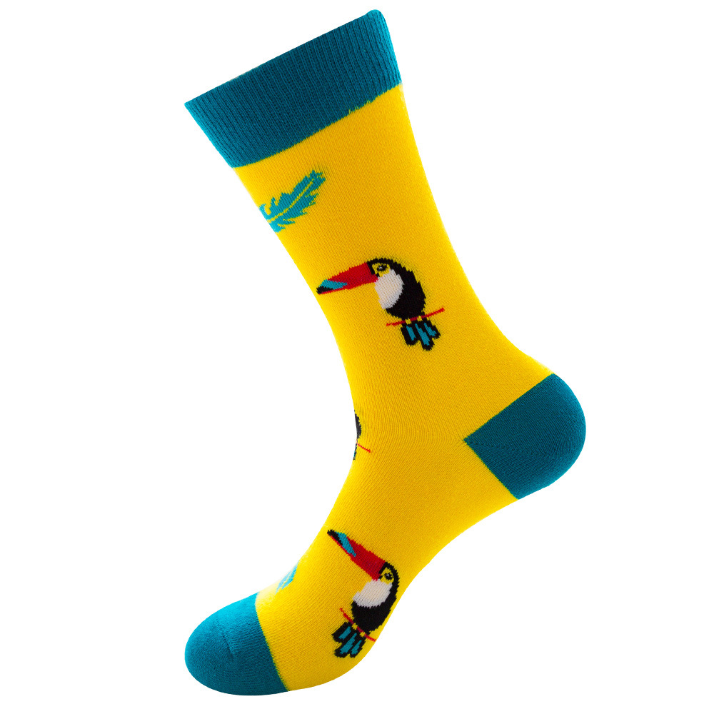 A pair of yellow crew socks with a pattern of toucans and leaves on the ankle area and blue heels.